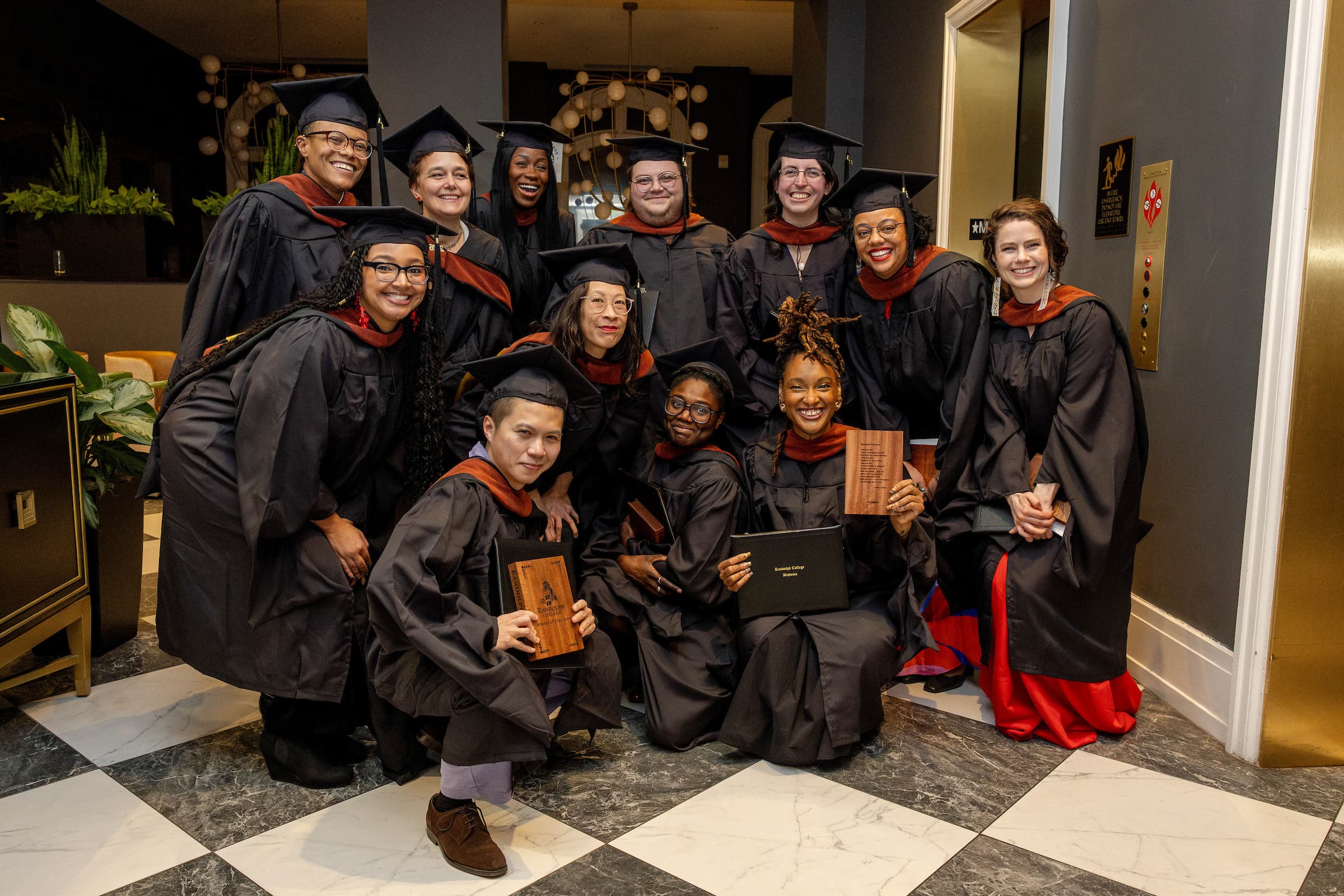 group picture of twelve smiling people in college graduation caps and gowns