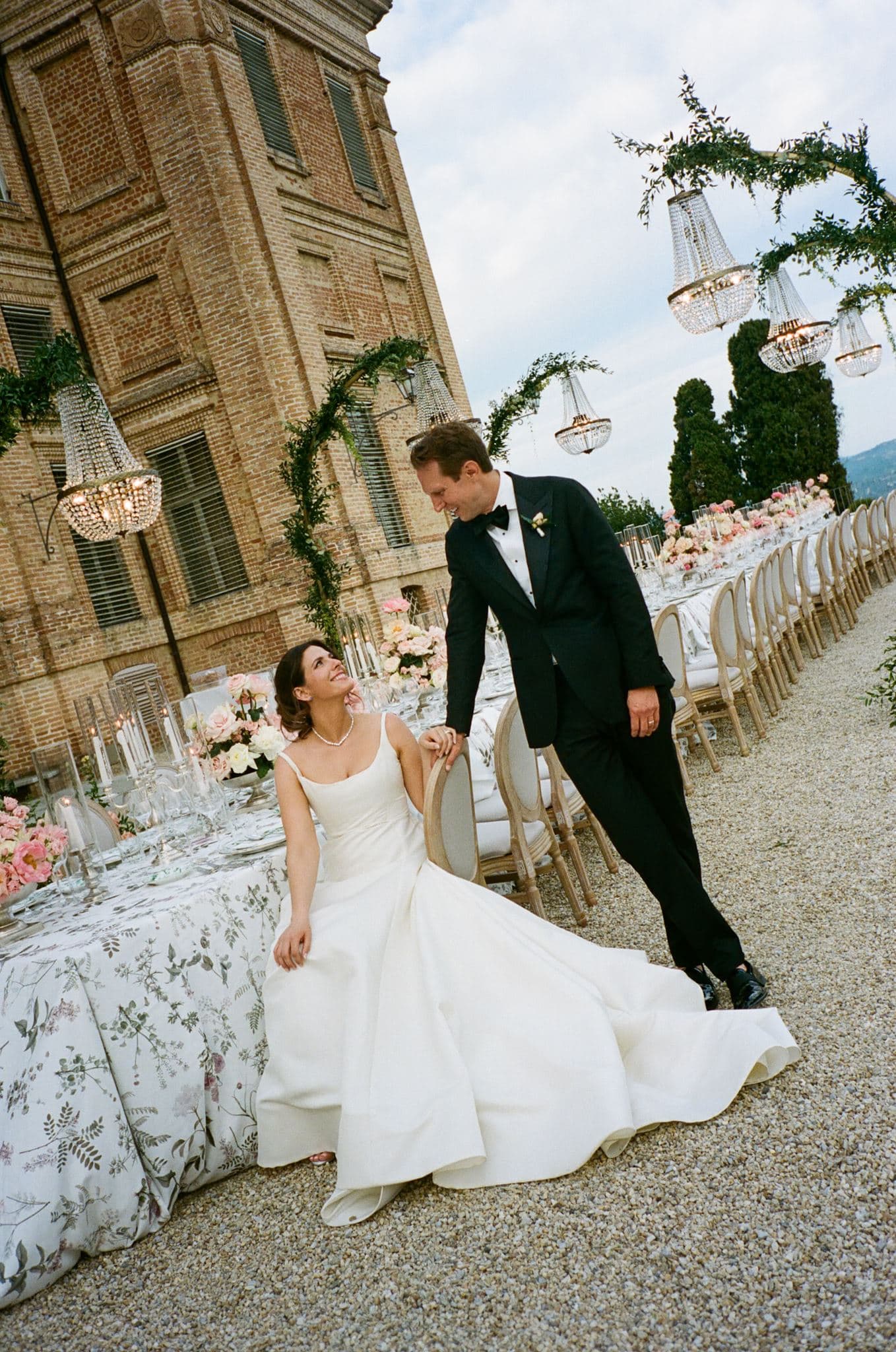 Bride Aimee and groom Dave gazing at each other in front of a long elaborately set wedding table.